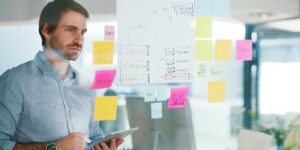 Shot of a young businessman using a digital tablet while having a brainstorming session in a modern office