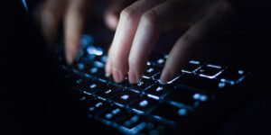Close-up shot of female hands typing on computer keyboard, working late at home.